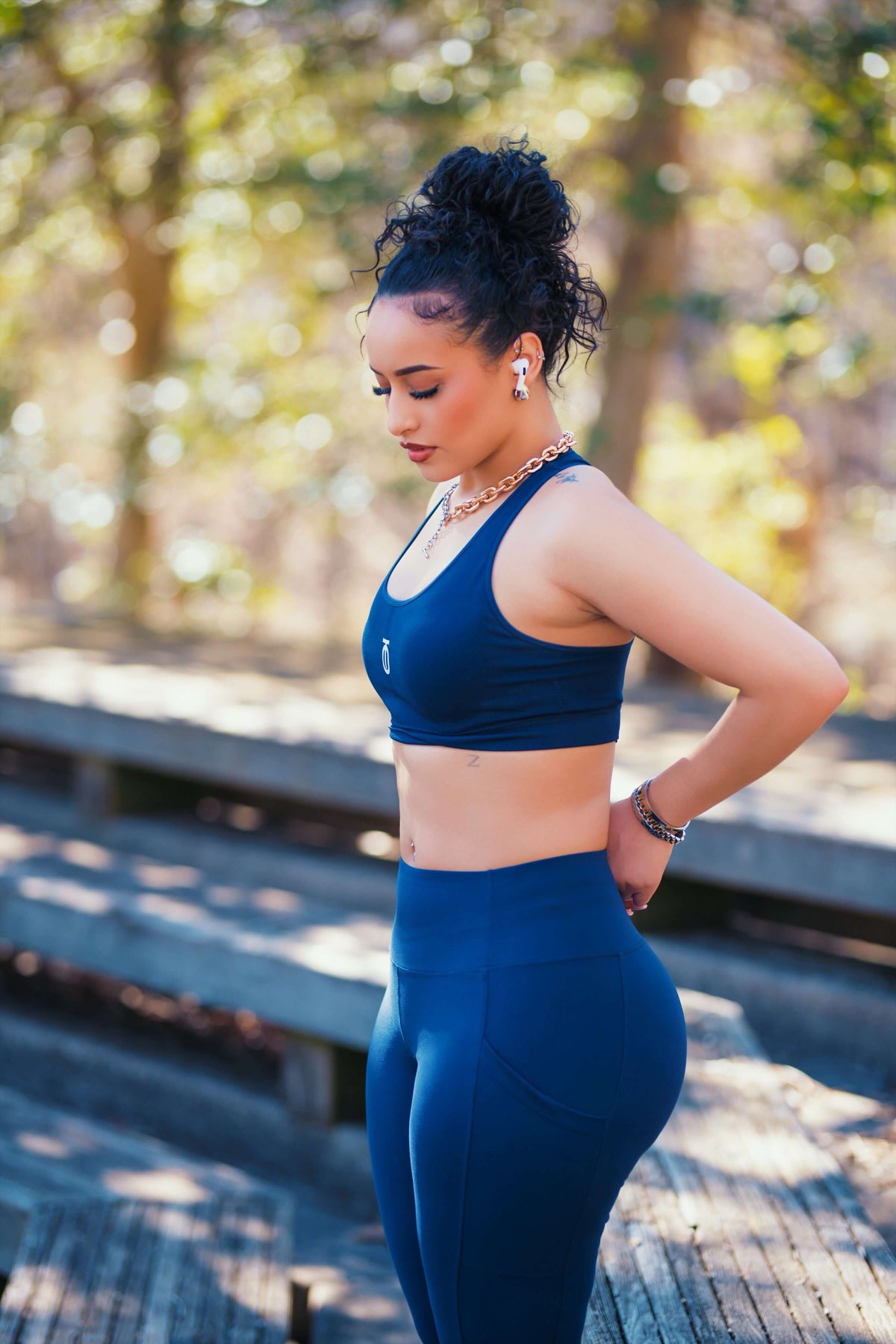 Side view of woman wearing navy Take One Sportswear Power Mesh Leggings and matching sports bra on an outdoor wooden deck.