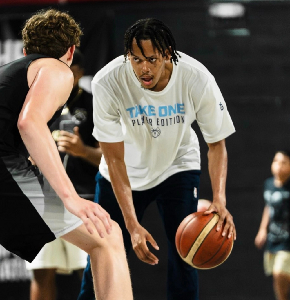 Jeff Dowin wearing a Take One Sportswear Player Edition shirt while training on an indoor basketball court.