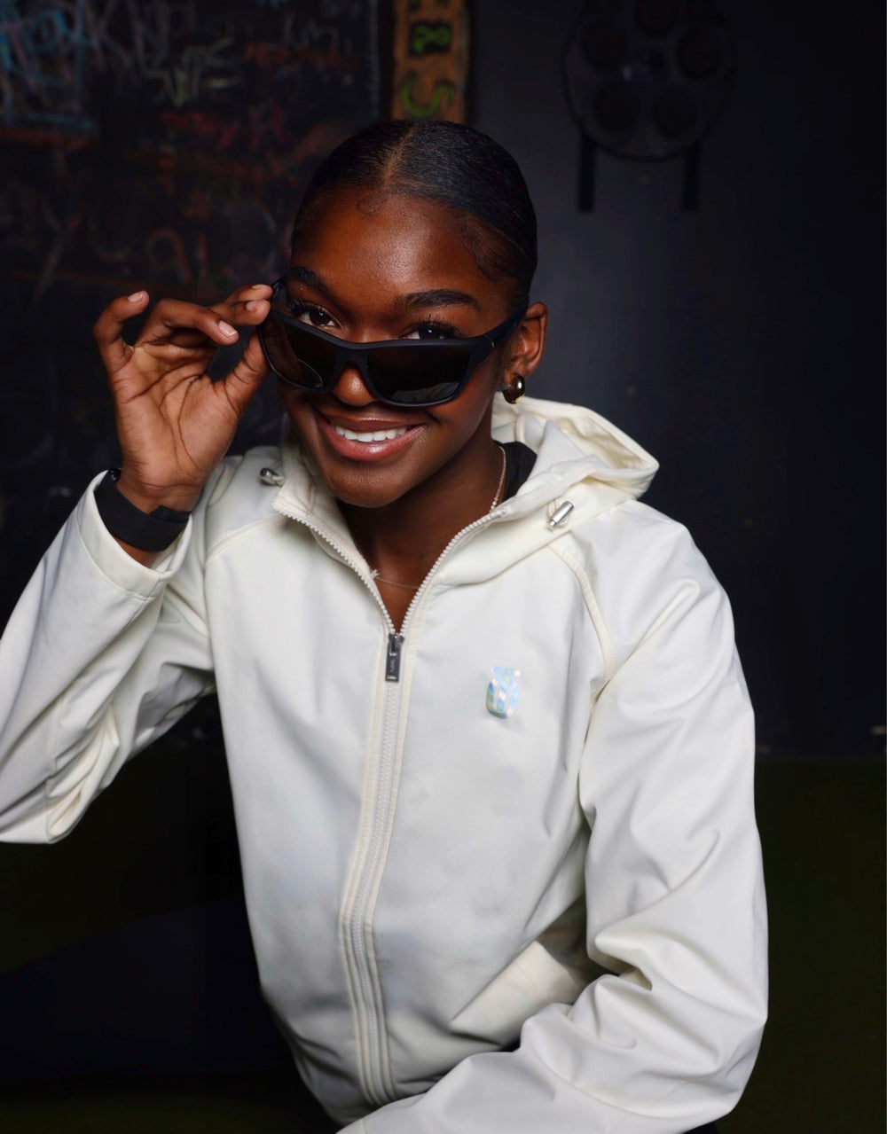 Kassidy Hopkins wearing a white Take One Sportswear jacket and black sunglasses.