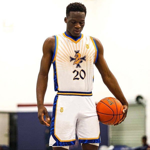 Basketball player wearing a custom Take One Sportswear uniform while holding a basketball on the court.