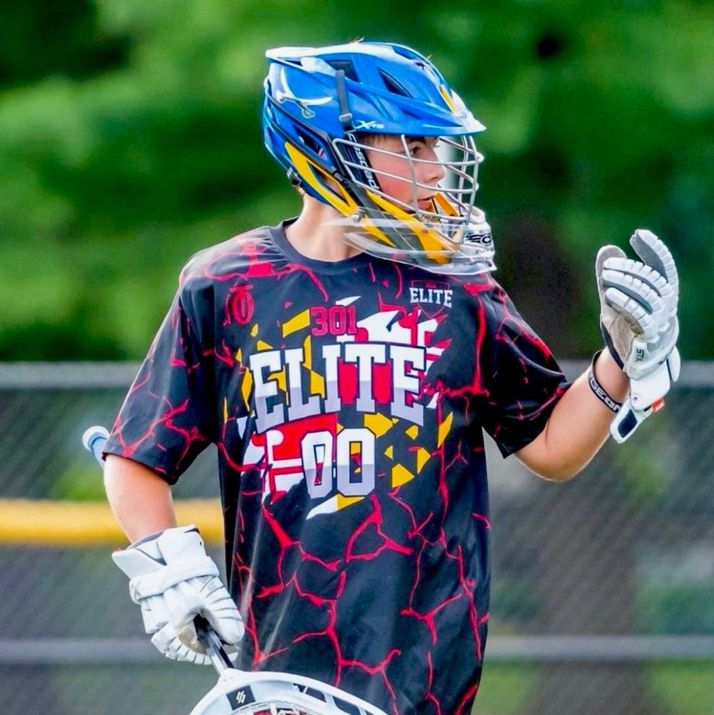 Lacrosse player wearing custom Take One Sportswear uniform while holding a lacrosse stick on the field.