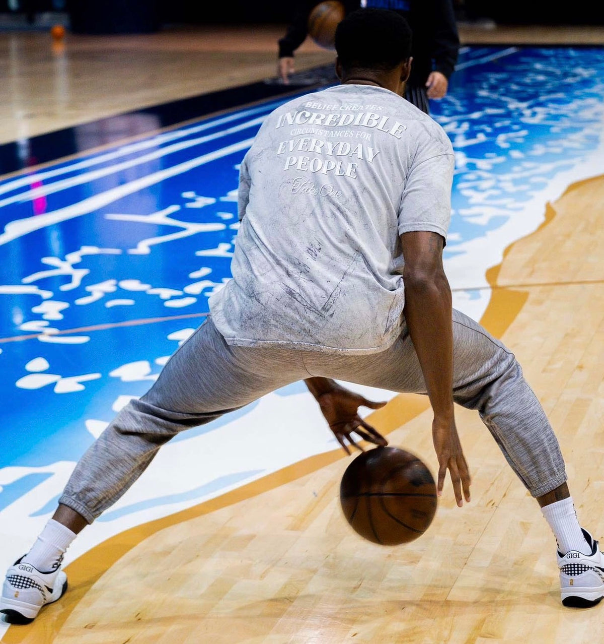 NBA player Haywood Highsmith wearing the Take One Sportswear Everyday People Tee while dribbling a basketball on an indoor court.