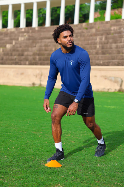 Athlete wearing royal blue Take One Sportswear Circuit Mesh Long Sleeve during an outdoor football agility training drill.