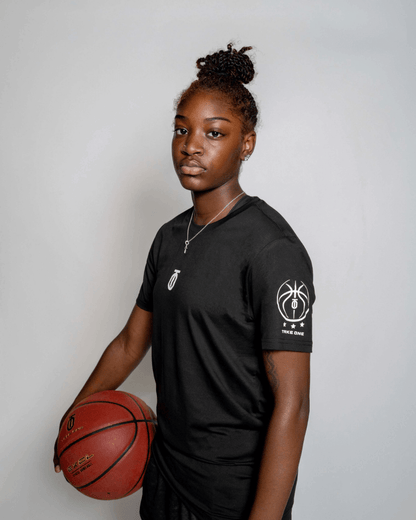 Female basketball athlete wearing the black Take One Sportswear Core Baselayer and holding a basketball in a studio portrait.