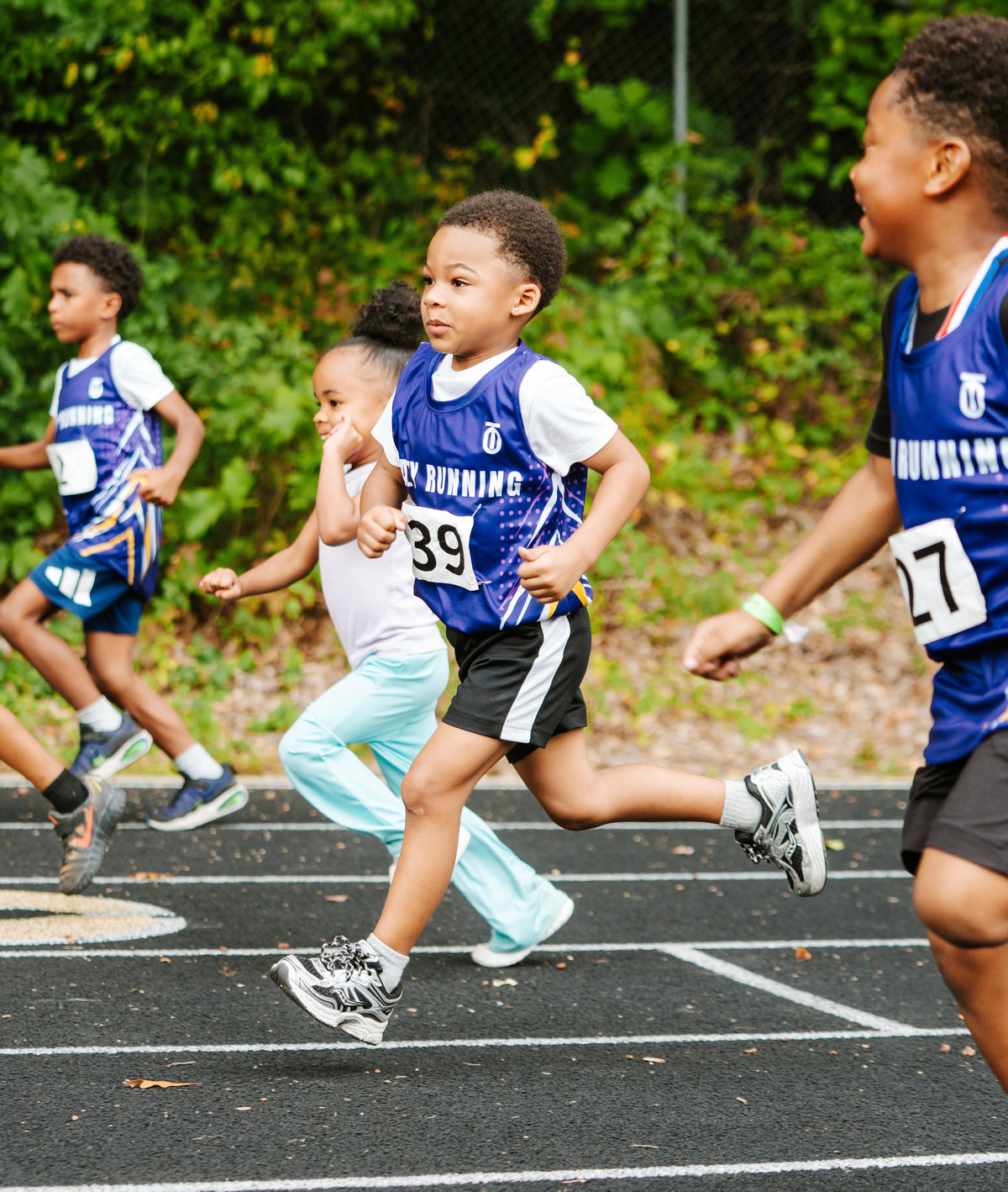 Youth runners in blue uniforms racing on a track, Take One Sportswear