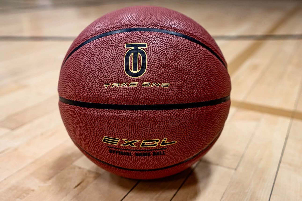Take One EXCL Basketball photographed from an alternate angle on an indoor basketball court floor.