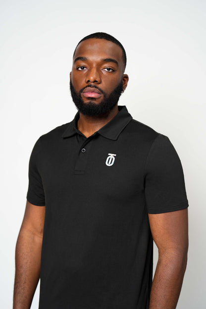 Front view of black Take One Journey Performance Polo featuring a classic collar, short sleeves, and small white chest logo.