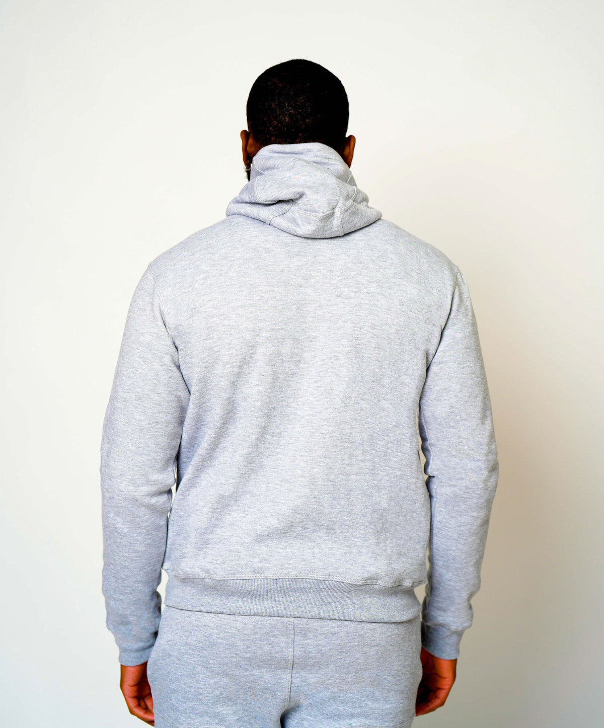 Back view of light grey Take One PeakPro Fleece Pullover worn by a male model, showing the hood and full-length sleeves.