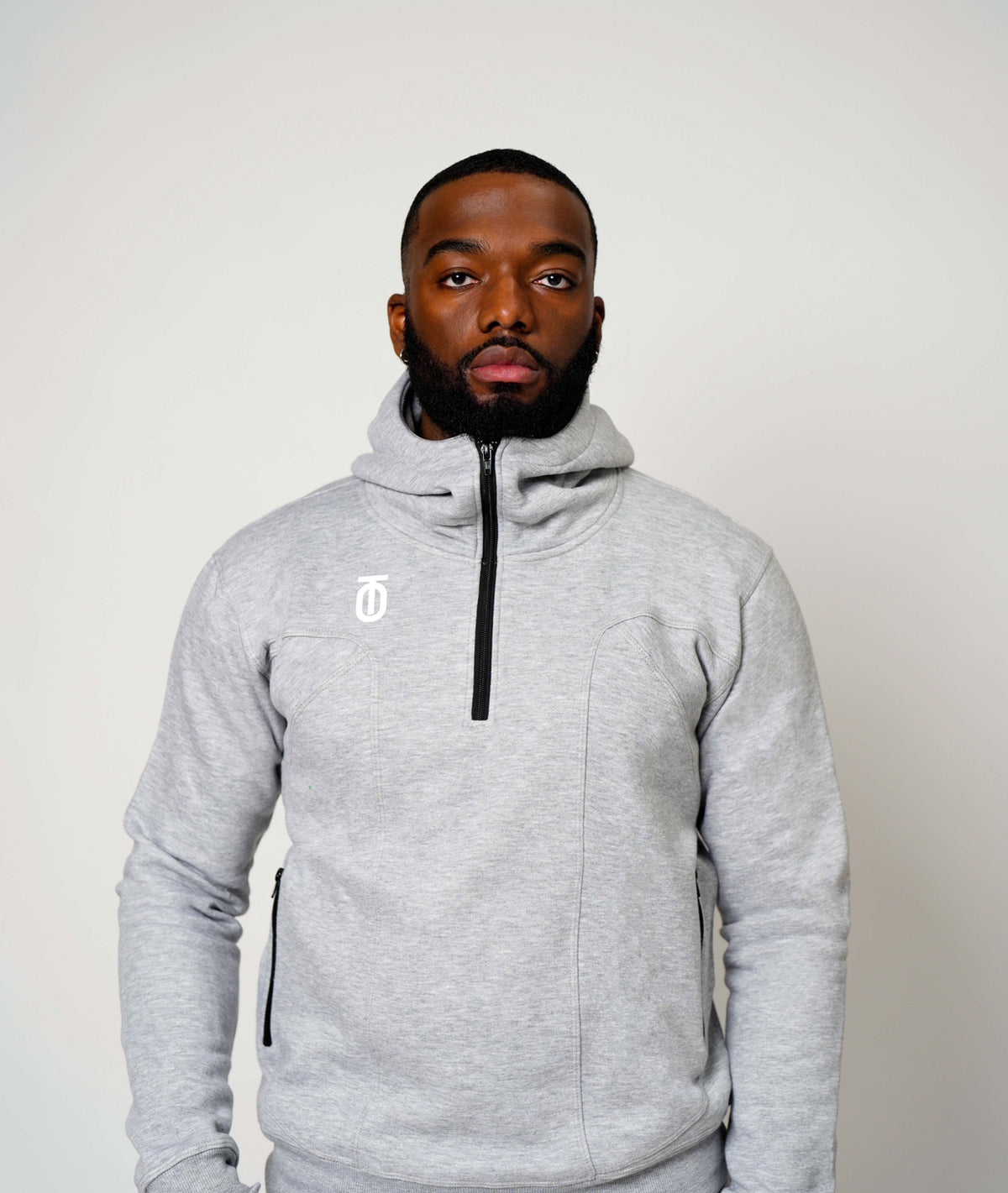 Front view of male model wearing a light grey Take One PeakPro Fleece 3/4 Zip Pullover with hood and black zipper.