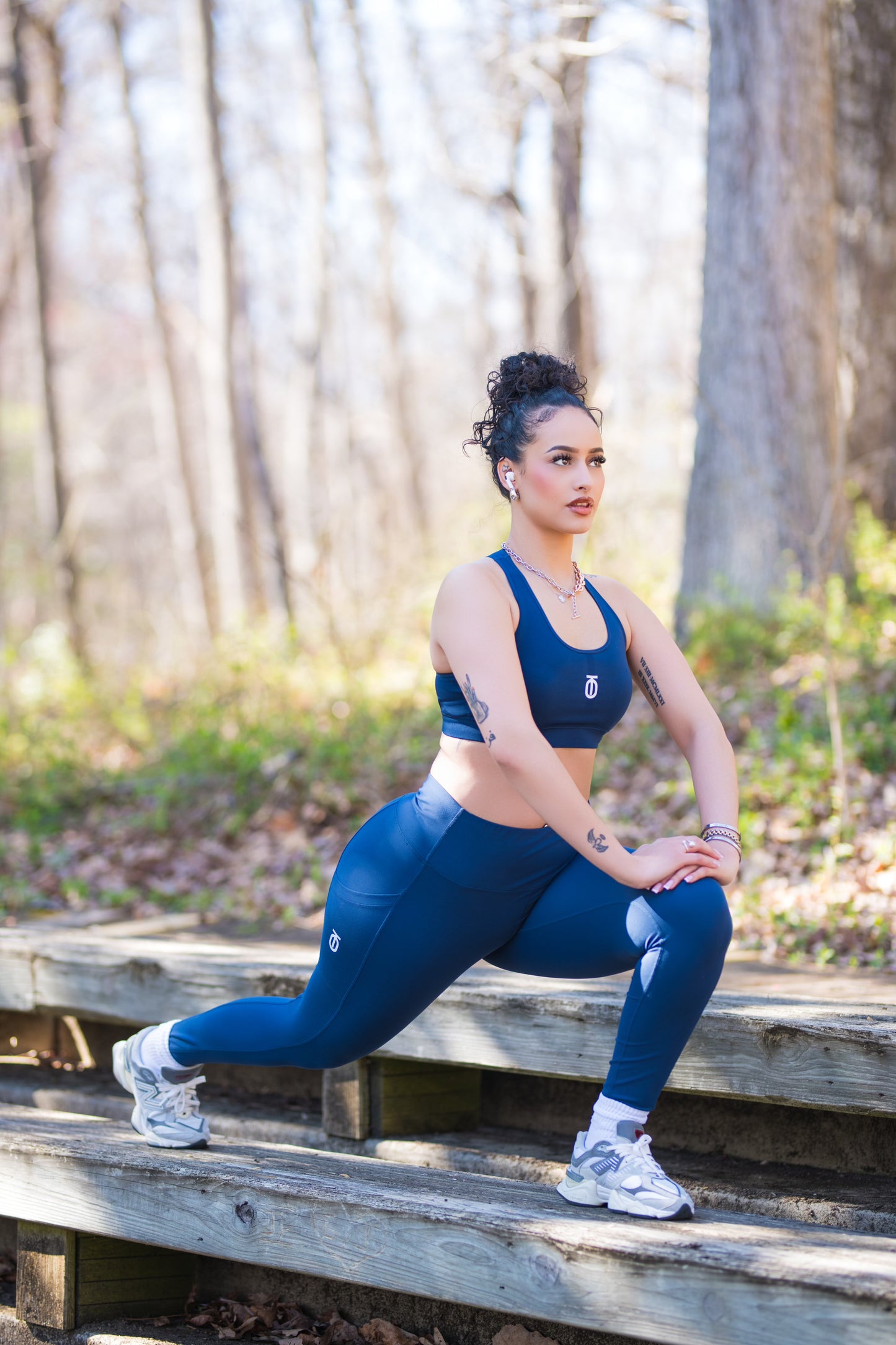 Woman wearing navy Power Mesh Leggings by Take One Sportswear while stretching on a wooden bench outdoors.