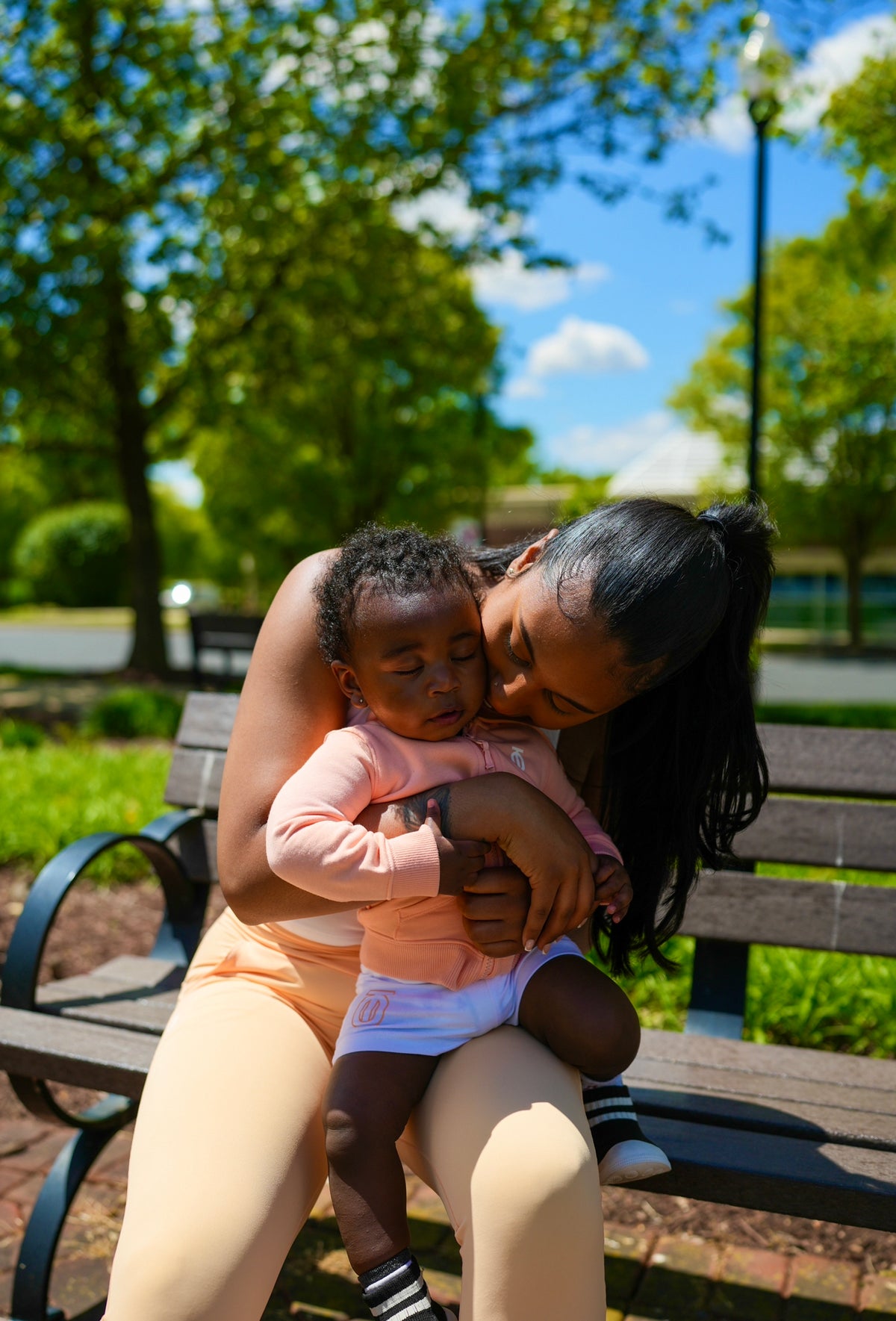 Toddler wearing Take One Sportswear athletic shorts while sitting with an adult on a park bench