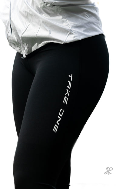 Close-up of black Take One Athena women's performance leggings showing the streamlined fit and Take One branding.