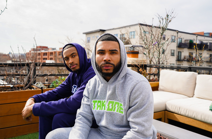 Two men modeling Take One Sportswear Prime Pullover Hoodies in purple and grey during an outdoor lifestyle photoshoot.