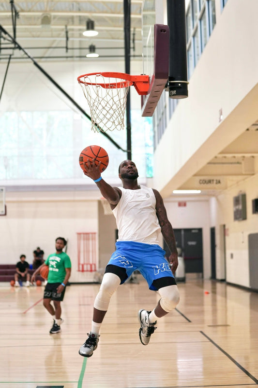Former NBA player Ty Lawson wearing Take One Sportswear NextGen Blitz basketball shorts while driving for a layup during an indoor basketball game.