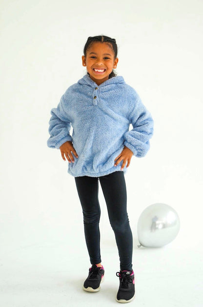 Smiling child modeling the light blue Take One Tundra Kids Fleece Hoodie with black leggings in a studio photoshoot.